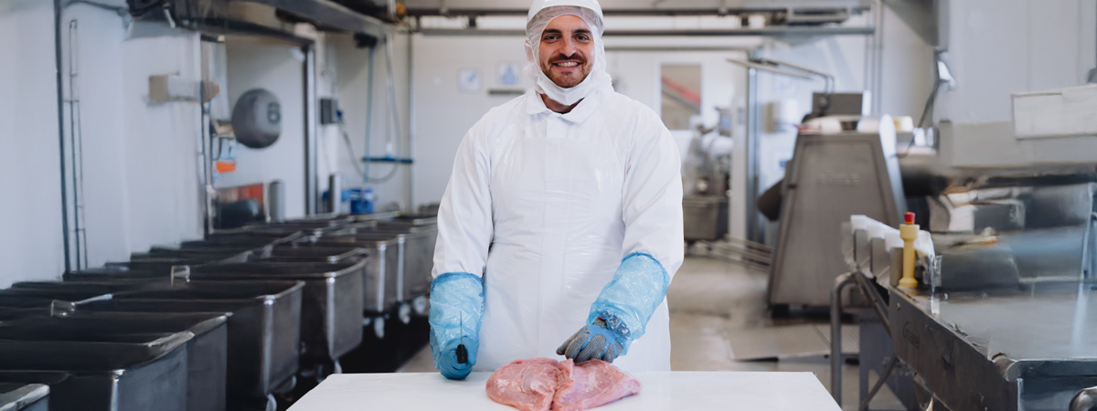 Eine Person in hygienischer Arbeitskleidung steht in einer industriellen Umgebung.