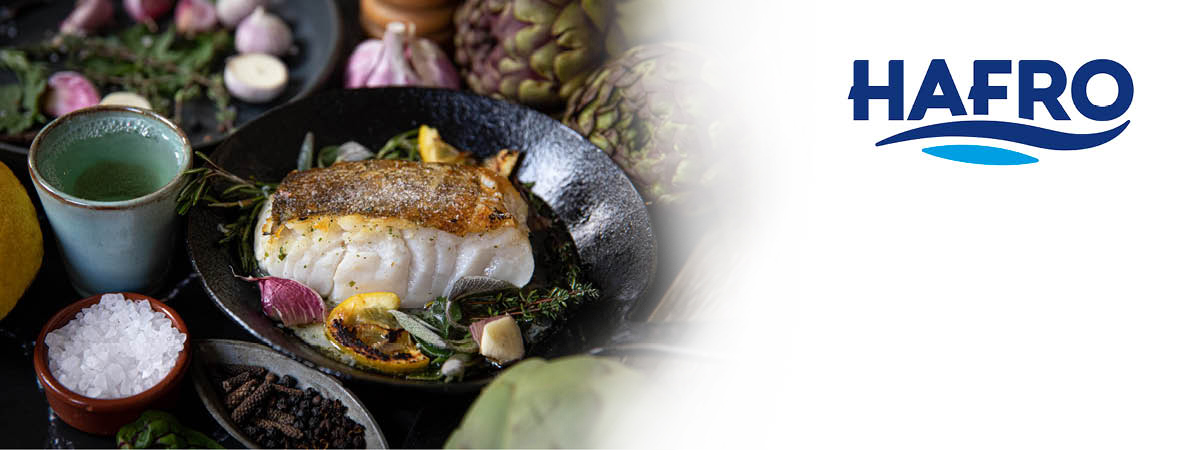 Ein Teller mit einem angerichteten Fischgericht, umgeben von frischen Zutaten wie Kräutern, Knoblauch, Zitrone und Gewürzen, präsentiert eine fein abgestimmte Mahlzeit.